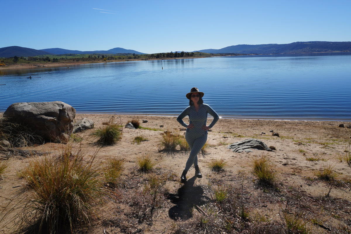 Woman wearing a blue Kunama Australian merino base layer beside a mountain lake